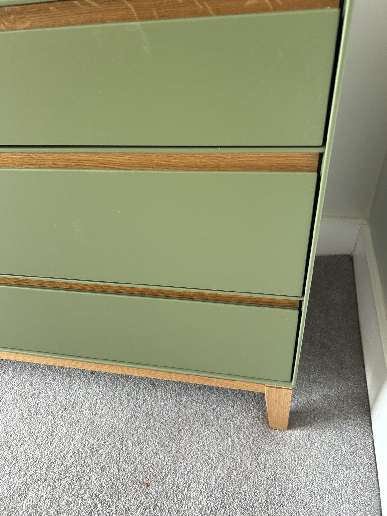 Detail of the oak trim between the olive green drawer fronts of the Heal's Lars chest