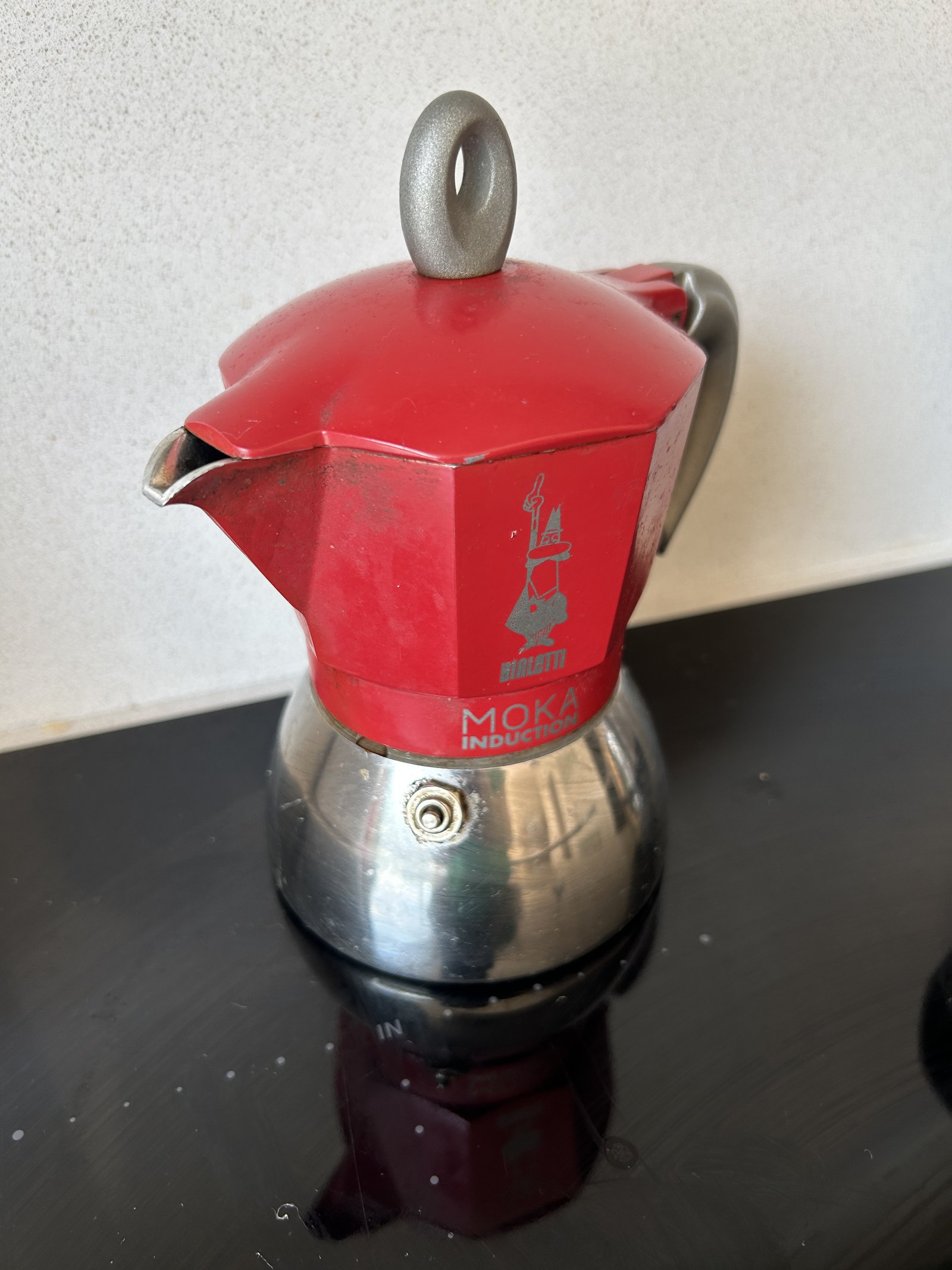 Two Bialetti Moka Induction pots, a red four-cup and a black six-cup, on the hob