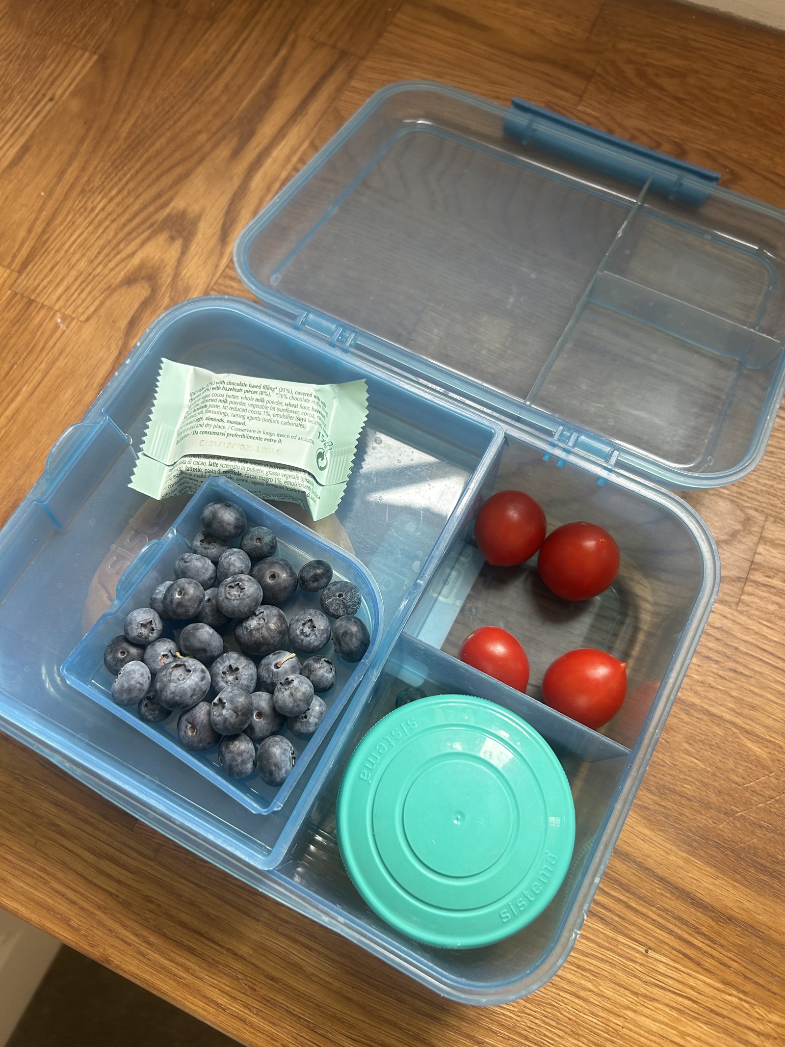 Sistema lunchbox packed with blueberries, cherry tomatoes and a wrapped snack