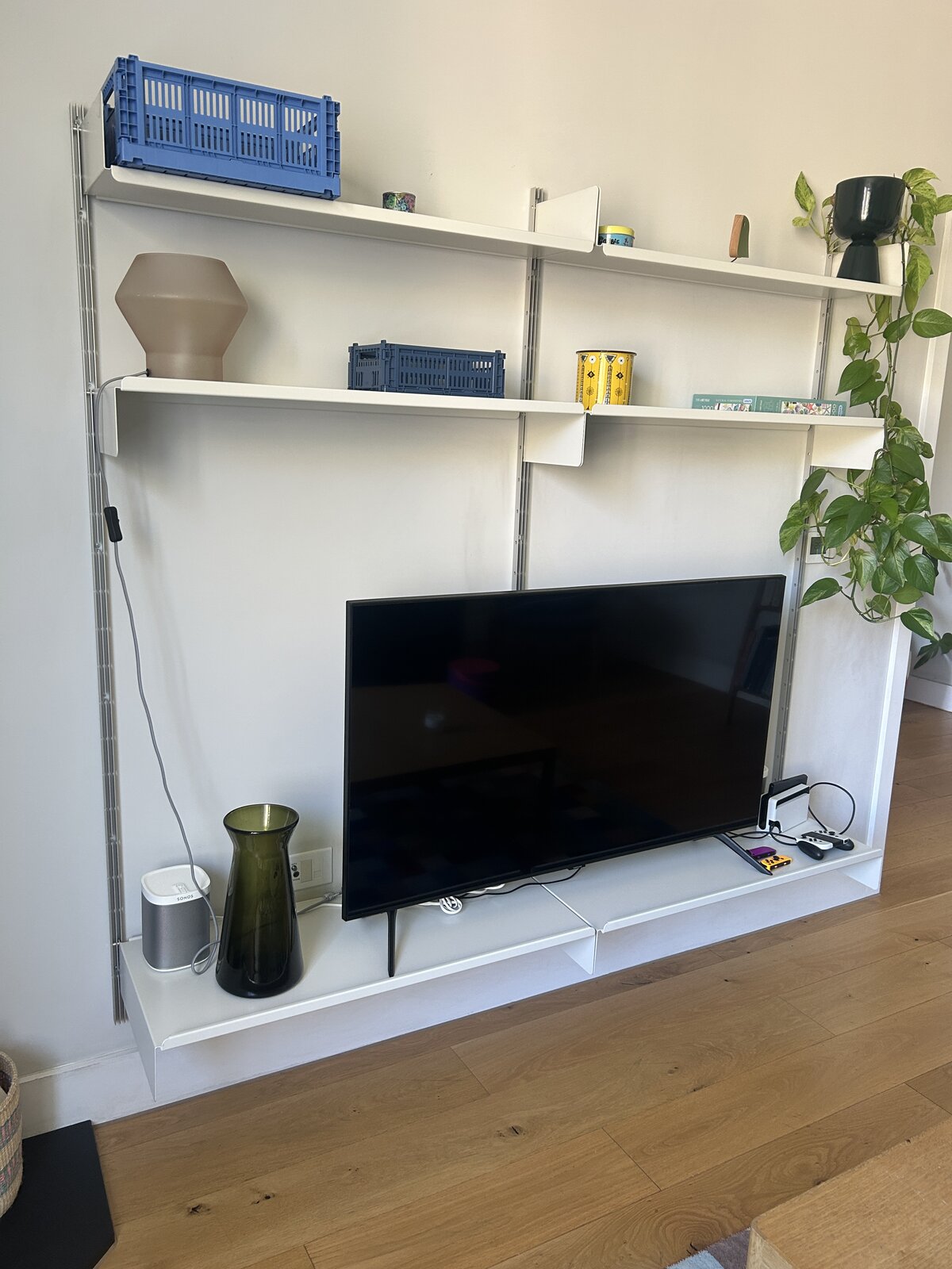 Vitsœ 606 shelving unit on the living room wall, holding the TV
